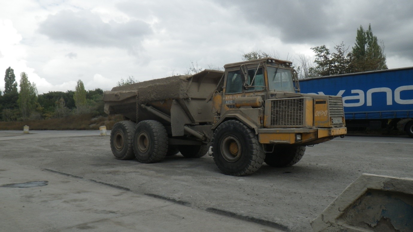 Yellow articulated dump truck covered in dirt