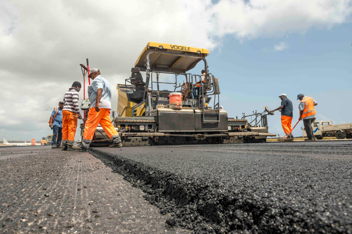 Workmen in orange hi-vis around tarmac laying machine