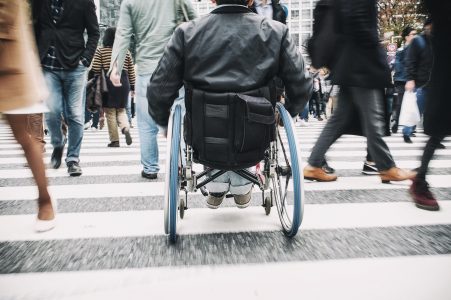 Wheelchair user navigating their way through pedestrians walking