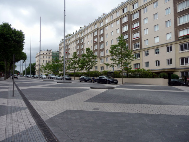 Cars parked along apartment buildings on a brick road